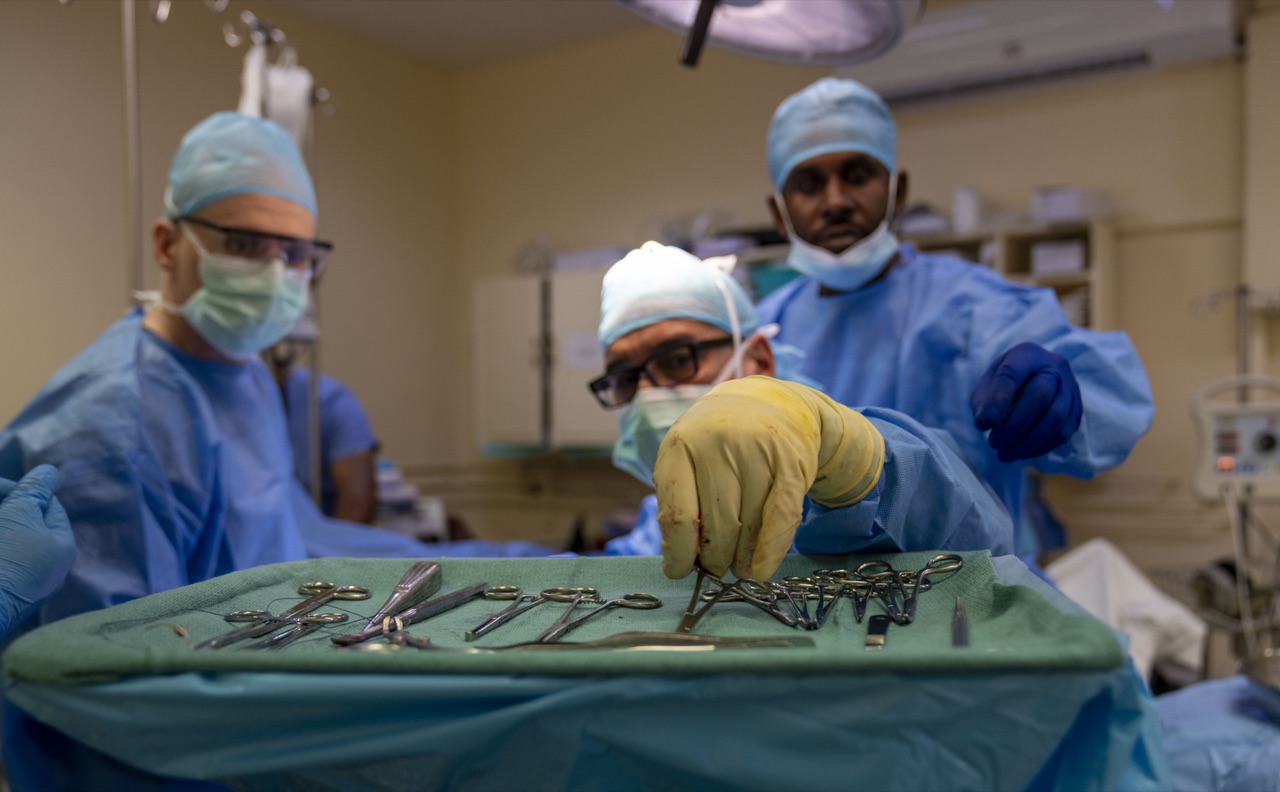 Orthopedic surgical team reaching for instruments on a sterile tray